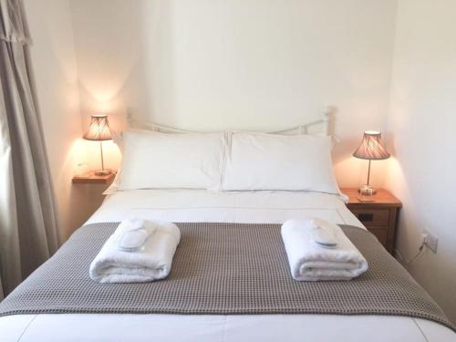 Chy Bownder Cottage في لوستويزيل: غرفة نوم بها سرير مع مناشف عليه