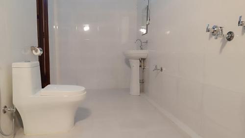 ein weißes Bad mit einem WC und einem Waschbecken in der Unterkunft Mr. B's Place in Bhurkīā
