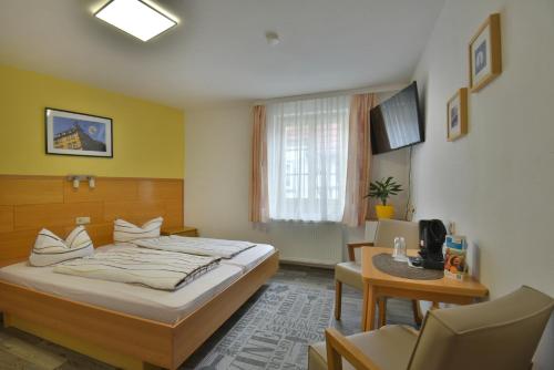 a bedroom with a bed and a desk and a chair at Pension Bergstube in Bad Langensalza