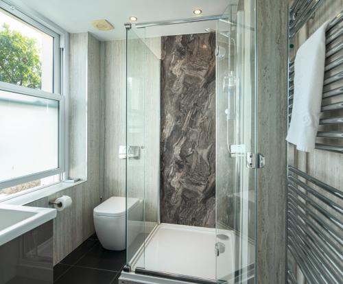 a bathroom with a toilet and a glass shower at Westwood Guest House - Room Only in Lyme Regis