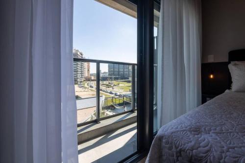 a bedroom with a bed and a large window at Loft 508 Inn - Parque Una in Pelotas