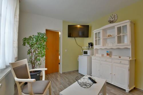 a kitchen with white cabinets and a tv on the wall at Pension Bergstube in Bad Langensalza