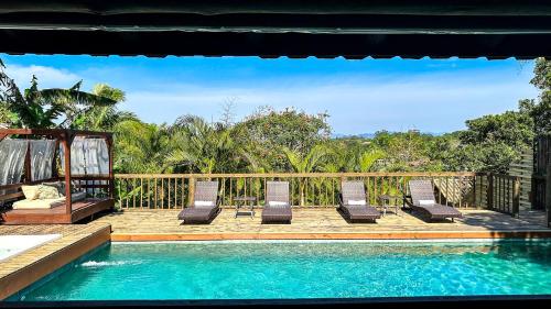 a group of chairs sitting on a deck next to a swimming pool at Morada da Praia do Rosa Pousada in Praia do Rosa