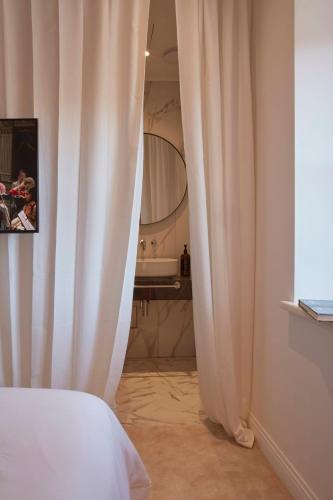a bedroom with white curtains and a bathroom with a tub at The Townhouse in Udine