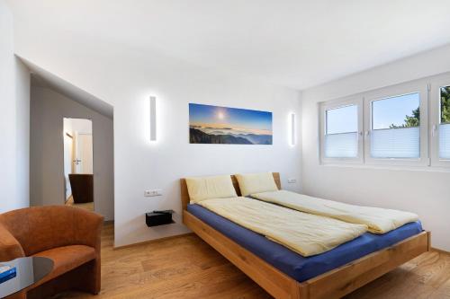ein weißes Schlafzimmer mit einem Bett und einem Stuhl in der Unterkunft Wolf's Apartment Schwarzwald in Renchen
