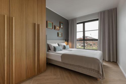 ein Schlafzimmer mit einem Bett und einem großen Fenster in der Unterkunft Solidarność Three Bedroom & Garden Apartment in Danzig
