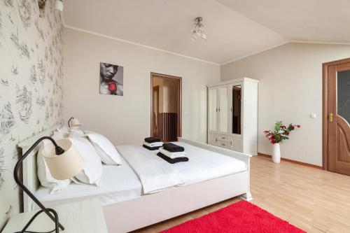 リヴィウにあるAlfa Apartments Ohiienka 17 2の白いベッドと赤いラグが備わる白いベッドルーム1室が備わります。