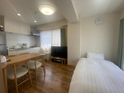 a room with a table and a bed and a kitchen at Mezon Akihabara Guest House in Tokyo