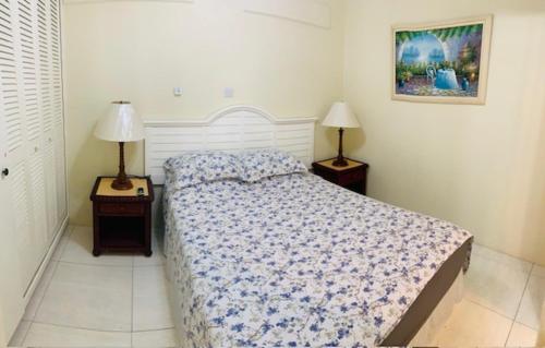 ein Schlafzimmer mit einem Bett und zwei Endtischen mit Lampen in der Unterkunft Apartment 1, Kenridge Residences in Saint James