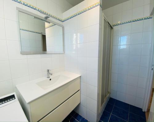 La salle de bains blanche est pourvue d'un lavabo et d'un miroir. dans l'établissement Appartement T4 Cité Cardaillac, Parking Privé, Wifi, à Rodez