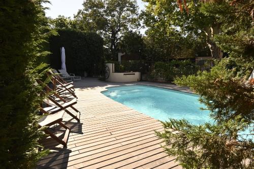 a swimming pool with chairs and a wooden deck at Bastide le Petit Clos - les 2 Gîtes in Perpignan