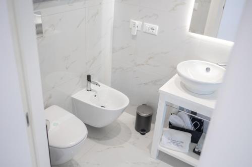 a white bathroom with a toilet and a sink at U Scrusciu d’u Mari Luxury Suite in Cefalù