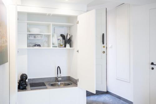 a kitchen with white cabinets and a sink at U Scrusciu d’u Mari Luxury Suite in Cefalù
