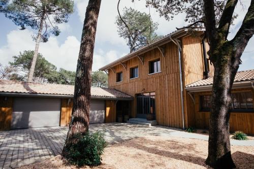 une maison avec des arbres devant elle dans l'établissement La Maison du Lac, à Lacanau