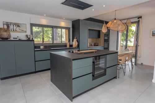 une cuisine avec des armoires bleues et un comptoir noir dans l'établissement La Maison du Lac, à Lacanau