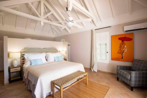 a bedroom with a large bed and a chair at Villa La Josephine, Terre Basses in Baie Longue