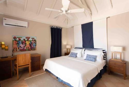 a bedroom with a white bed and a ceiling fan at Villa La Josephine, Terre Basses in Baie Longue
