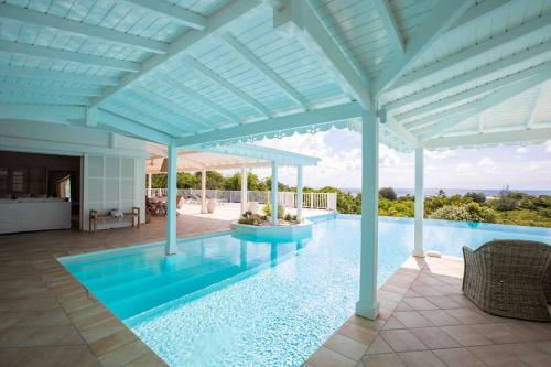 a large swimming pool with a large white pergola at Villa La Josephine, Terre Basses in Baie Longue