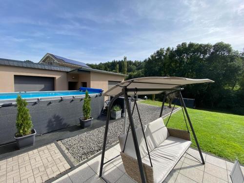 um pátio com uma cadeira e um guarda-sol ao lado de uma piscina em Eifel-Mosel-Hideaway em Landscheid