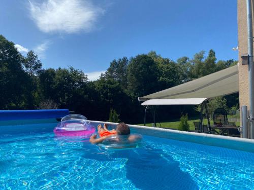 a man is in a swimming pool on an inflatable at Eifel-Mosel-Hideaway in Landscheid