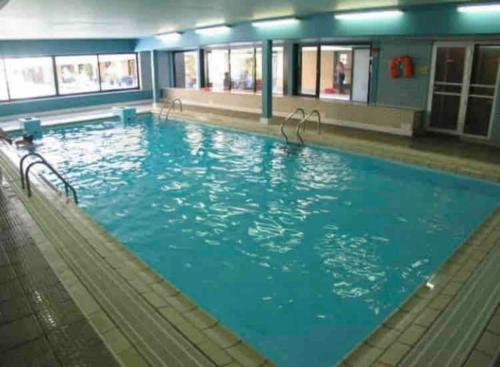 uma grande piscina com água azul num edifício em Sfeervol Appartement met Zeezicht em Middelkerke