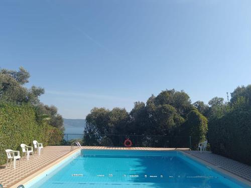 una piscina con 2 sillas blancas al lado en Le Petit Nid, en Toscolano Maderno