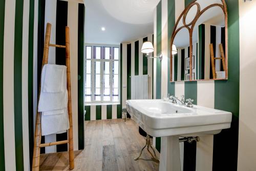 uma casa de banho com um lavatório branco e riscas verdes e brancas em Relais Villino Rubini em Brunate