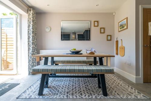 uma sala de jantar com uma mesa e um espelho em Fleming Cottage - Contemporary Cotswold Home 