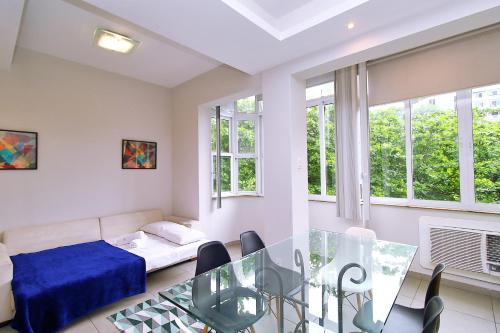 1 dormitorio con mesa de comedor, 1 cama y ventanas en Apartamento 3 quartos, 2 minutos andando até a praia T011 en Río de Janeiro