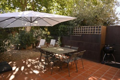 a patio with an umbrella and a table and chairs at Bastide le Petit Clos - les 2 Gîtes in Perpignan