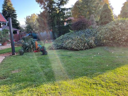 a man mowing the grass in a yard at Idill Üdülőház in Tiszafüred