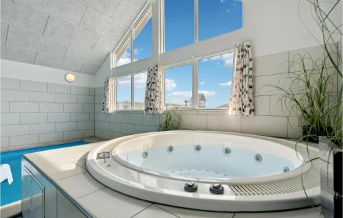 a large tub in a bathroom with windows at Amazing Home In Hvide Sande With House A Panoramic View in Havrvig