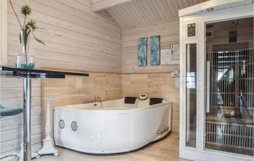 ロンストラップにあるStunning Home In Hjrring With 5 Bedrooms, Sauna And Internetの木製の壁の客室内に白いバスタブが備わります。