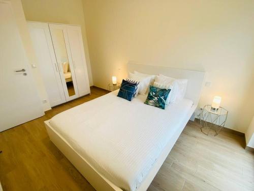 - un lit blanc avec des oreillers bleus dans une chambre dans l'établissement Luxury 2023 Flat in city center with Parking-HOL1, à Luxembourg