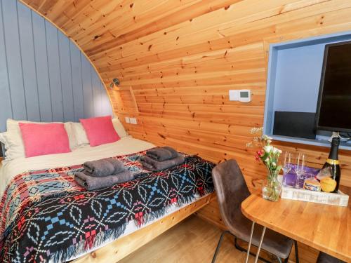 a bedroom with a bed and a table and a television at Conwy Pod in Llanrwst