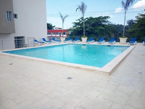 a large swimming pool with blue chairs at Boca del Mar, Torre II, Apto. 202 in Santo Domingo