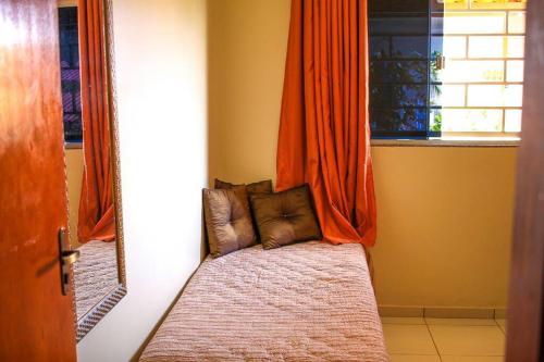 a room with a bed with an orange curtain at Casa em condomínio, churrasqueira privativa e piscina social in Caldas Novas