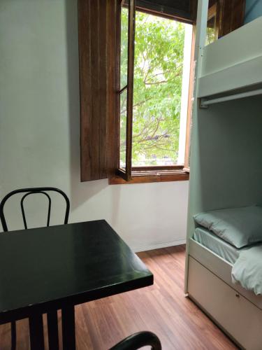 a small room with a table and a window at Fujima Hostel in Sao Paulo
