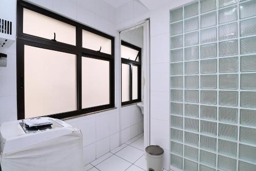 a white bathroom with windows and a toilet at Apartamento 3 quartos, 2 minutos andando até a praia T011 in Rio de Janeiro