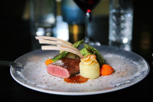 a plate of food with meat and vegetables with a fork at Van Der Valk Hotel Zwolle in Zwolle