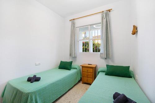 2 camas individuales en una habitación con ventana en Las Golondrinas, en Chiclana de la Frontera