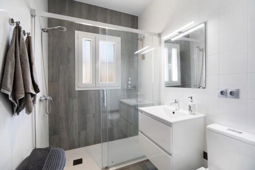 a white bathroom with a shower and a sink at Las Golondrinas in Chiclana de la Frontera