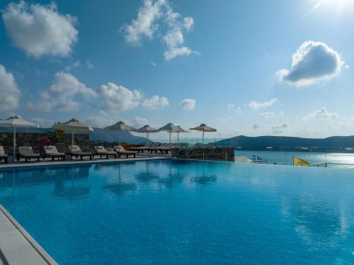 a large swimming pool with chairs and umbrellas at Royal Marmin Bay Boutique & Art Hotel in Elounda