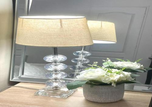 a lamp and a vase of flowers on a table at LIVABLŌM " Petit Dej Offert " in Guesnain