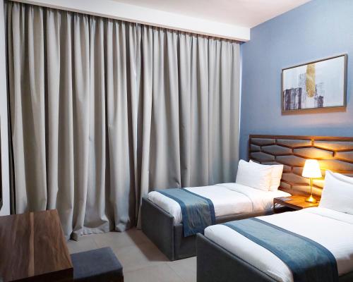 a hotel room with two beds and curtains at Luxe Grand Hotel Apartments in Sharjah