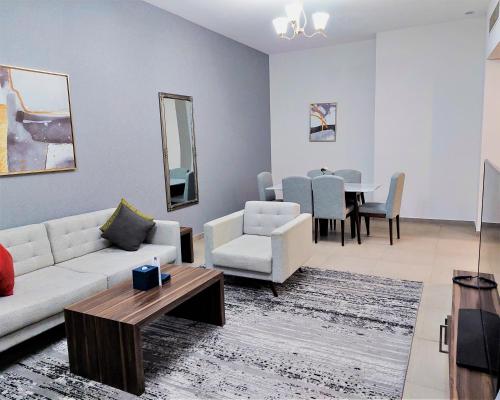 a living room with a couch and chairs and a table at Luxe Grand Hotel Apartments in Sharjah