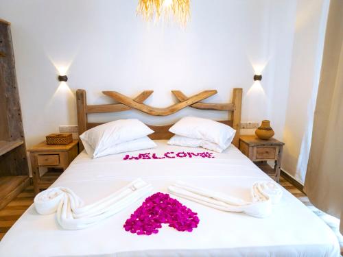 a bedroom with a white bed with pink flowers on it at Limiria Villa Zanzibar in Nungwi