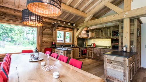 une salle à manger avec une table en bois et des chaises rouges dans l'établissement Chalet Chal'heureux, à Chamonix-Mont-Blanc