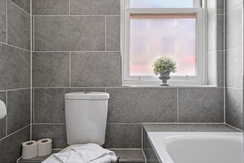 a bathroom with a toilet and a window and a tub at Camden Cottage, 2 Bedroom house in Camden Town in London