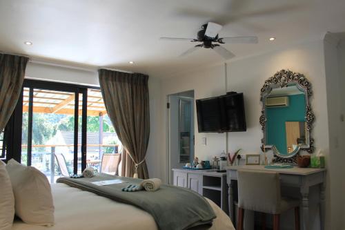 a bedroom with a bed and a desk and a mirror at Pelican Lodge Guesthouse in Sedgefield